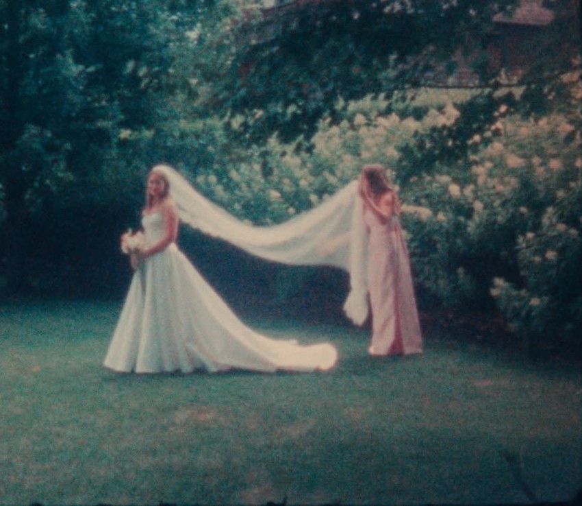 Bride and bridesmaid with a long veil in the garden, Super 8 still